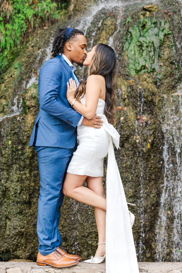 Bride and groom to be kiss in front waterfall during a San Antonio engagement photo shoot