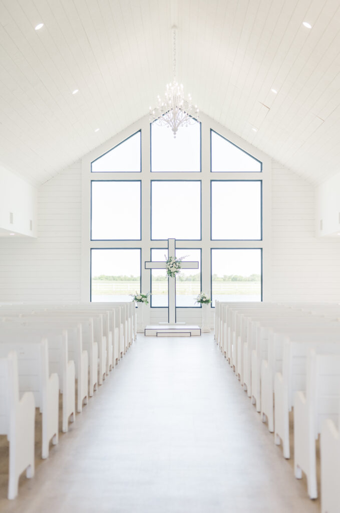 The Gardenia venue chapel for wedding ceremony with a cross at the front and white pews