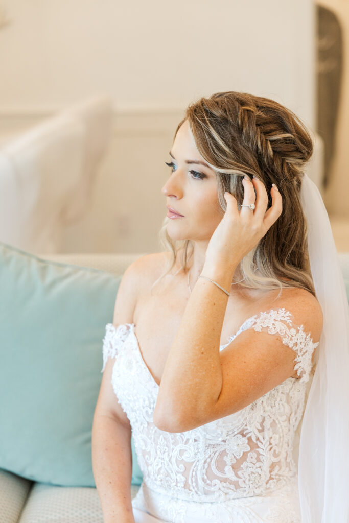 Dallas bride pulls back her hair with her ring on her hand showing looking at a window at the Gardenia venue