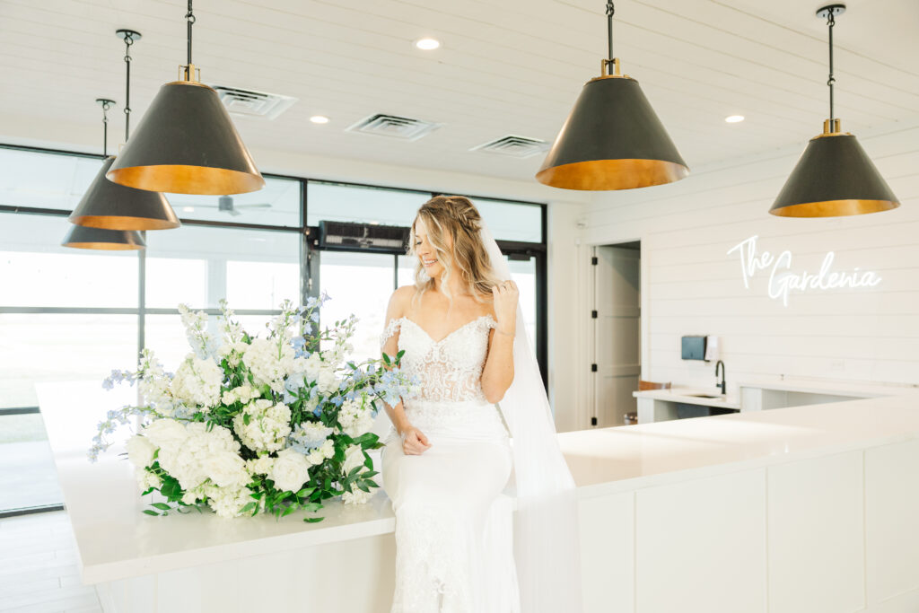 Dallas Bride looks down at flowers in the kitchen of The Gardenia Venue