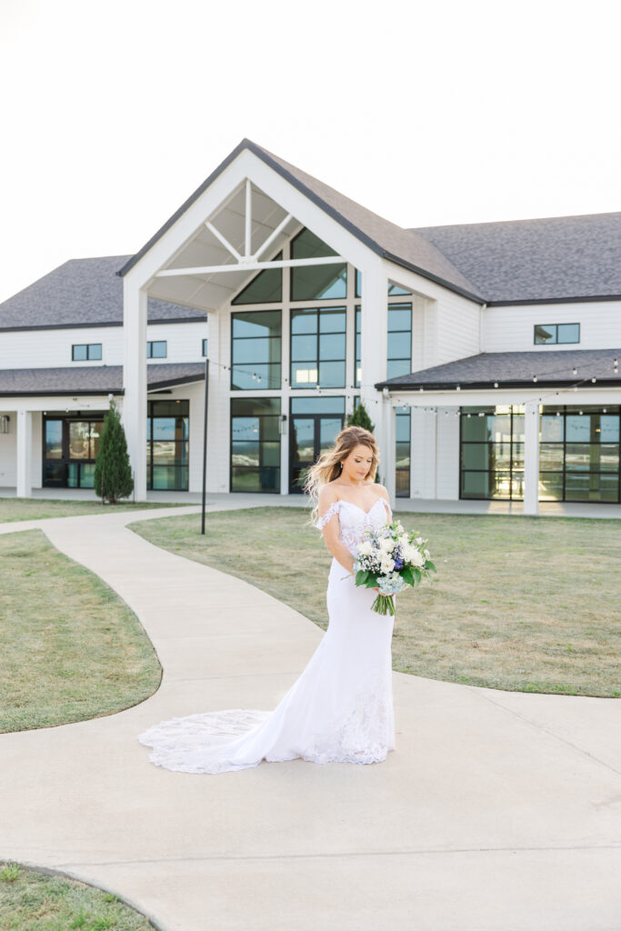 Dallas bride stands outside The Gardenia Venue with a bouquet of white and blue.