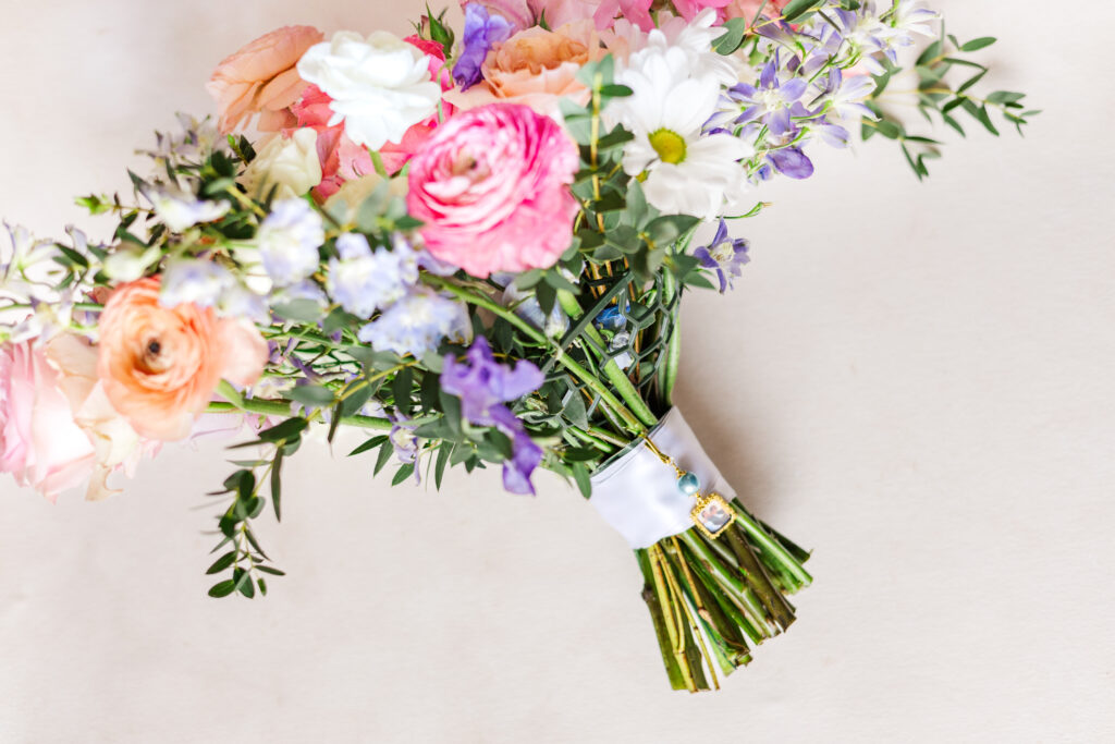 bride's bouquet with pink, orange, white, and blueish flowers put together by a San Antonio wedding florist