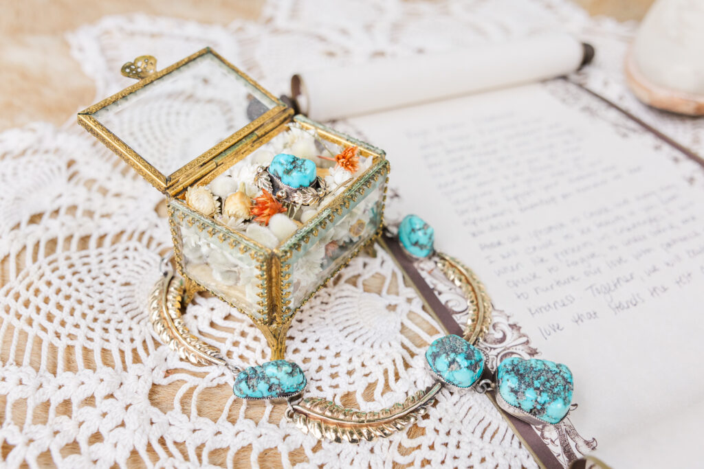 box of sea shells and a beautiful necklace lay on top of lace for a wedding flat lay photo