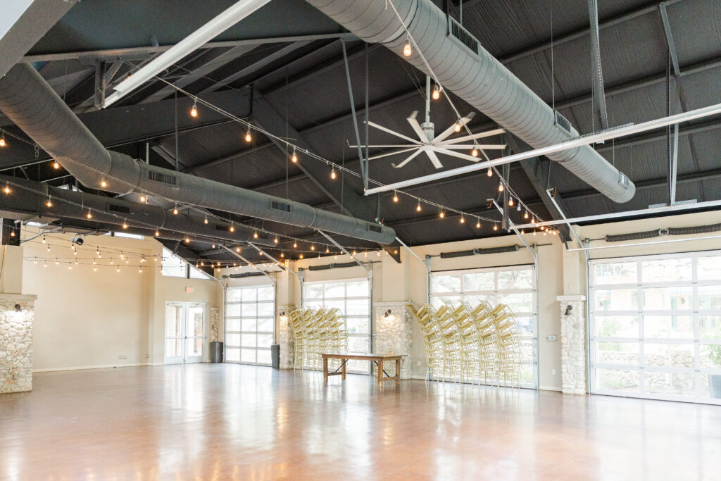 Dance hall with a lot of natural light from clear glass garage doors that can be pulled up during nice weather. A lot of chairs and a fireplace as well.