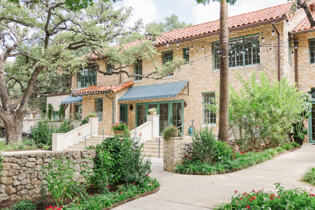 Back patio and stairs of The Veranda San Antonio wedding venue. Lights are strung up around the trees.