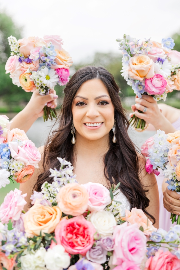  Bride is surrounded by her bridesmaids bouquets in front of a pond at a San Antonio wedding venue