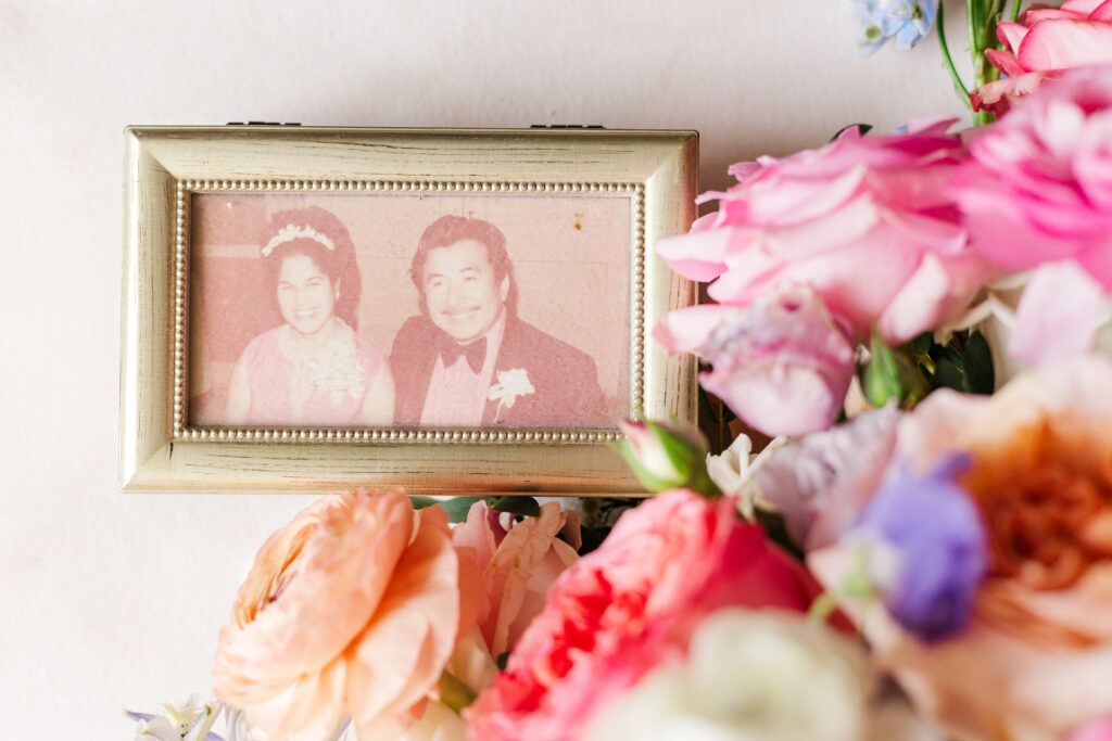 Photo of parents on their wedding day lay with the bride's bouquet for a wedding flat lay