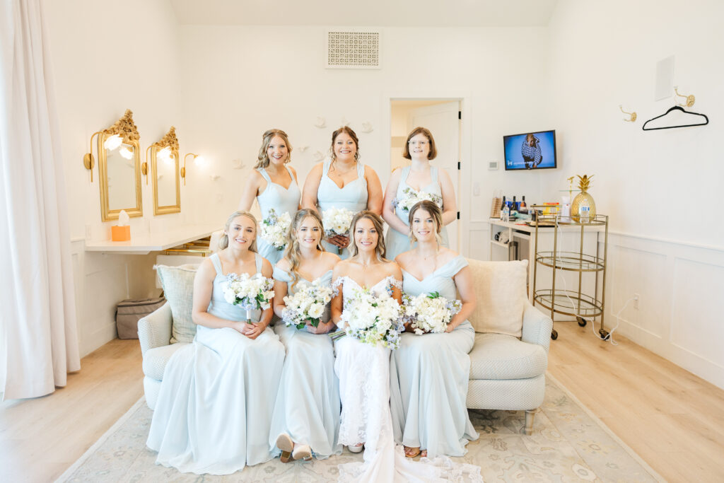 Bridesmaids sit around San Antonio bride for a formal photo in the getting ready room.