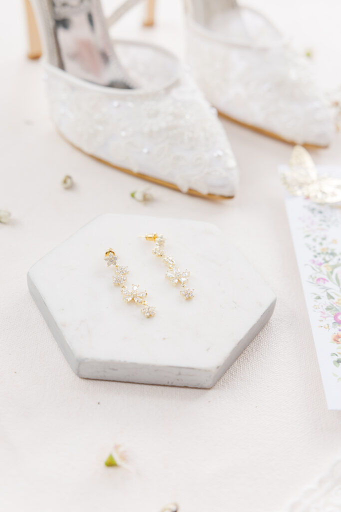 San Antonio wedding photographer captures long dangling earrings on a small platform. The earrings have diamonds in the shape of flowers all the way down