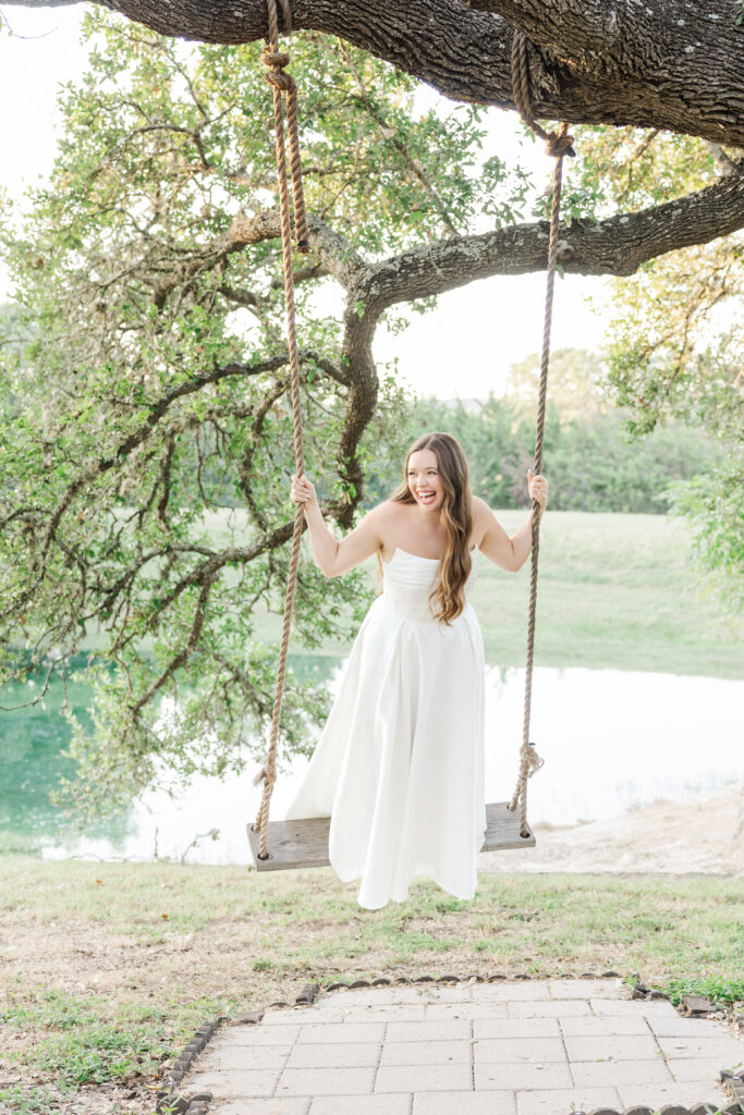 Bride swings on a rope swing attached to a tree in front of Kendall Point wedding venue